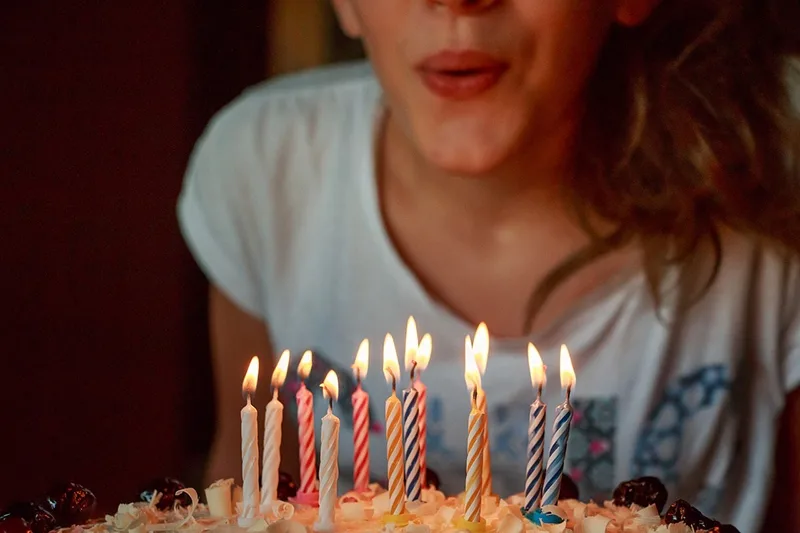 ein Mädchen, das Kerzen auf Kuchen bläst, um den 12. Geburtstag zu feiern
