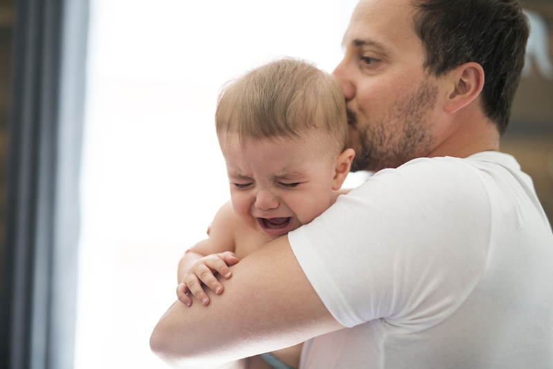 ein Vater, der ein weinendes Baby tröstet und es trägt