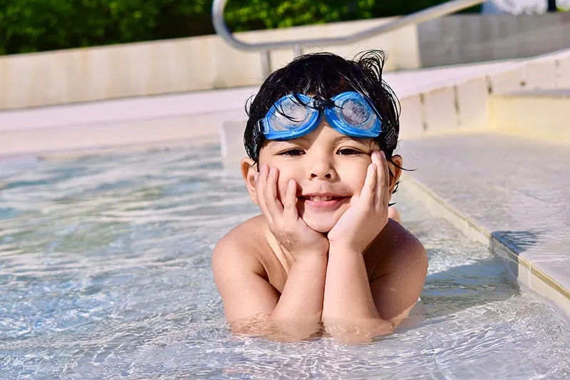 ein kleiner Junge in einem Schwimmbad, der sich auf seine Hände stützt
