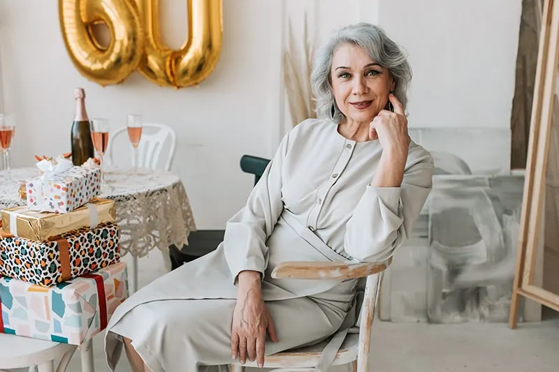 elegante ältere Frau sitzt auf dem Stuhl und feiert 60. Geburtstag