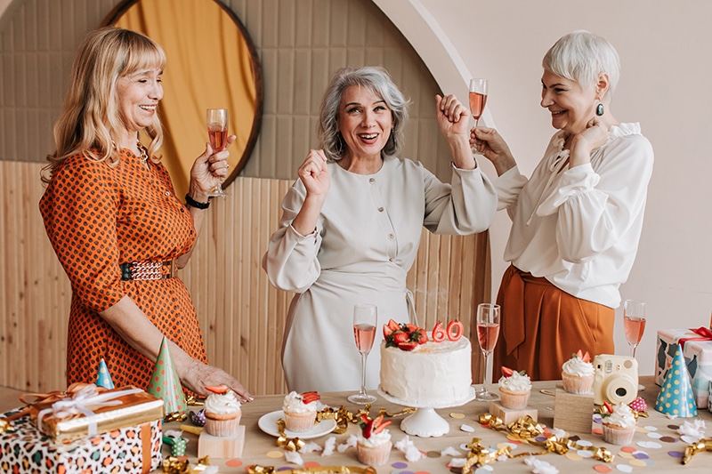 fröhliche ältere Frau feiert 60. Geburtstag mit Freunden