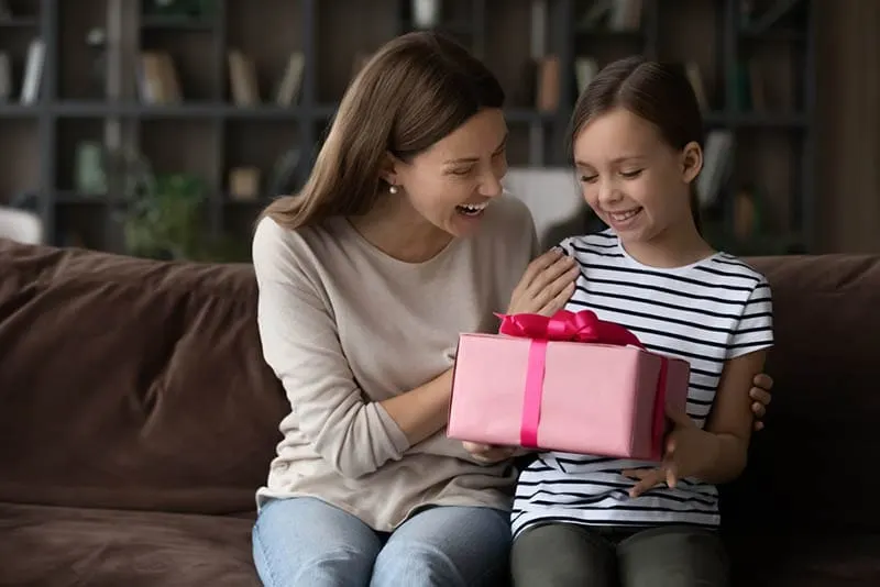 glückliche junge Frau, die ihrer Nichte ein Geschenk zum Geburtstag macht