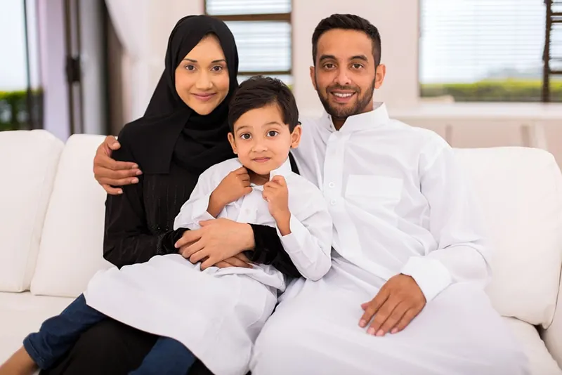 glückliche muslimische Familie, die zu Hause auf der Couch sitzt