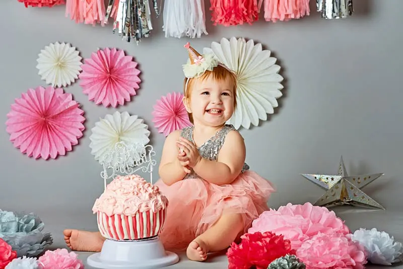 glückliches kleines Mädchen feiert Geburtstag mit Kuchen und Luftballons