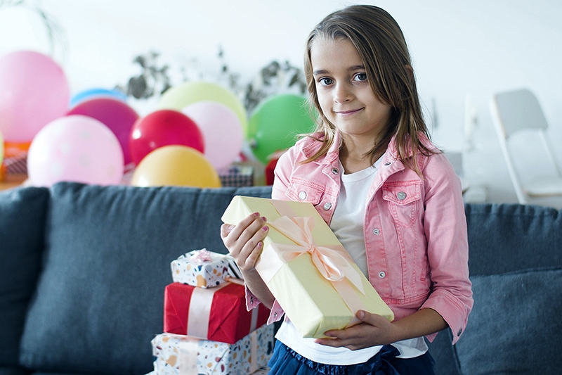 kleines Mädchen mit einem Geschenk auf ihrer Geburtstagsfeier