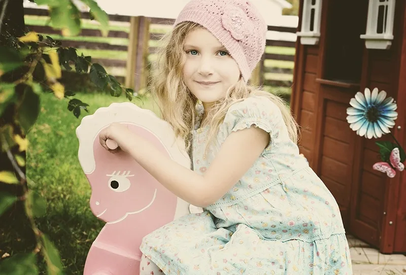 kleines Mädchen mit rosa Strickmütze auf dem Spielplatz