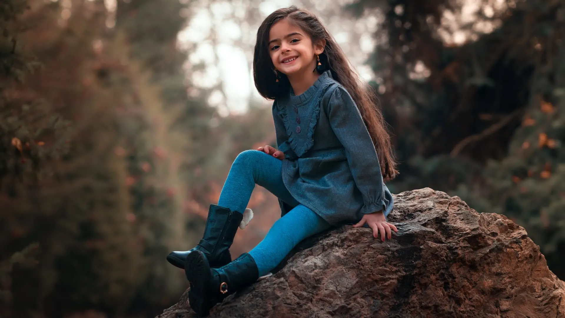 kleines Mädchen sitzt auf dem Felsen im Wald