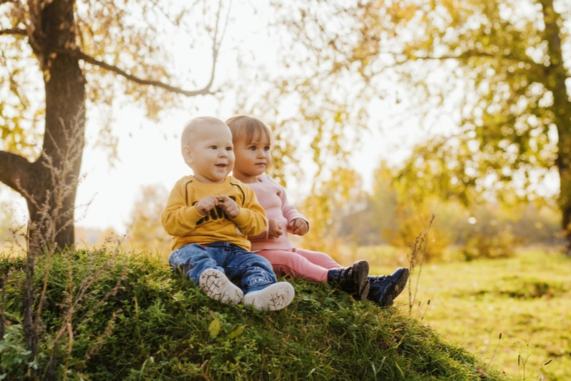 kleines Mädchen und Kleinkind sitzen auf dem Gras