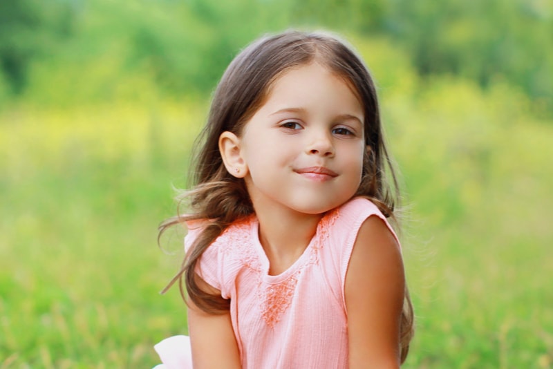 kleines Mädchenkind auf dem Gras am sonnigen Sommertag