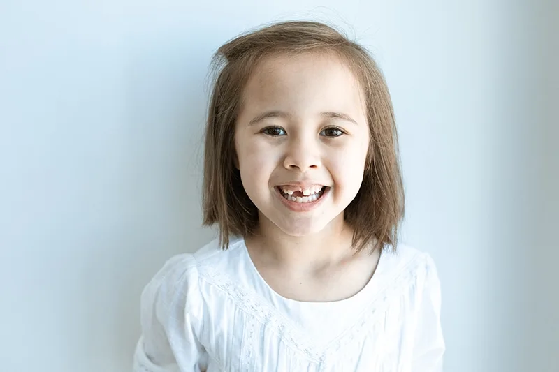 lächelndes kleines Mädchen mit kurzen Haaren in weißer Bluse