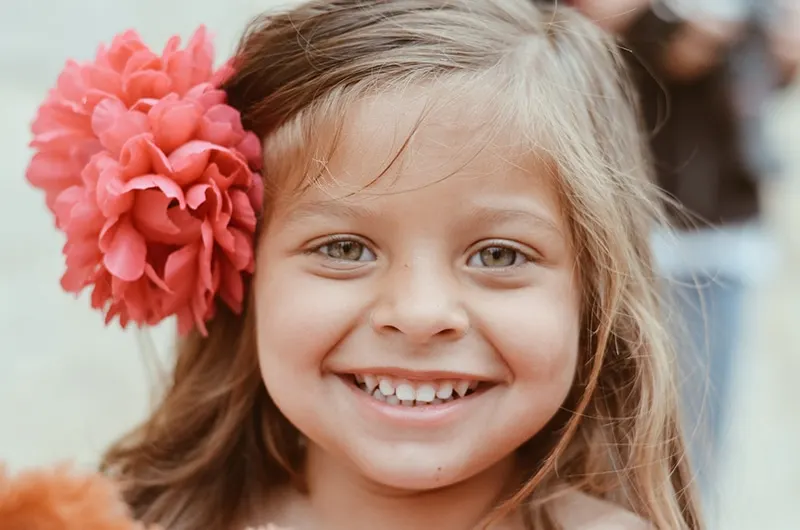 lächelndes kleines Mädchen mit rosa Blume im Haar