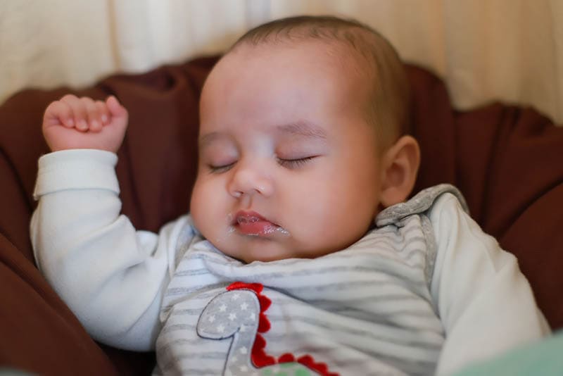  neugeborenes Baby im Bett schlafend mit verschmutztem Mund Erbrechen