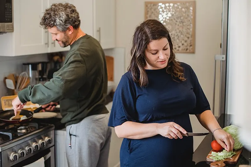 Schwangere Frau und ihr Mann bereiten Essen in der Küche zu