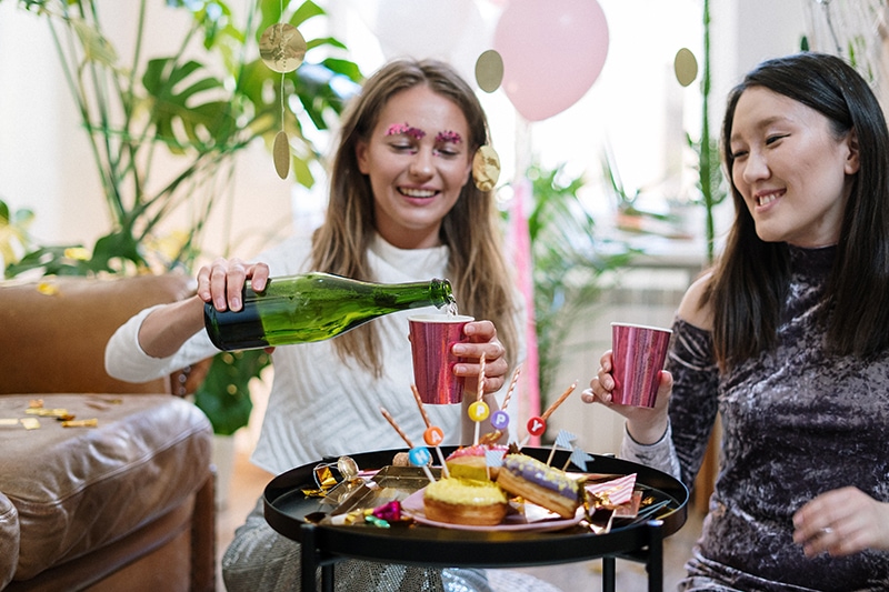 Zwei fröhliche Frauen trinken Champagner auf der Geburtstagsfeier