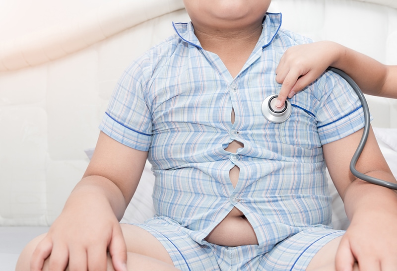 Arzt überprüft das Herz eines übergewichtigen Jungen mit einem Stethoskop