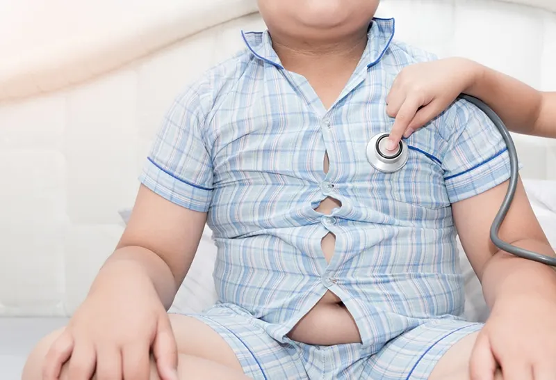 Arzt überprüft das Herz eines übergewichtigen Jungen mit einem Stethoskop