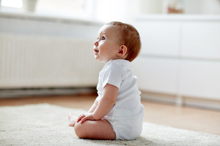 Baby sitzt auf dem Boden und schaut nach oben