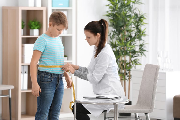 Ärztin, die Taille eines übergewichtigen Jungen in der Klinik misst