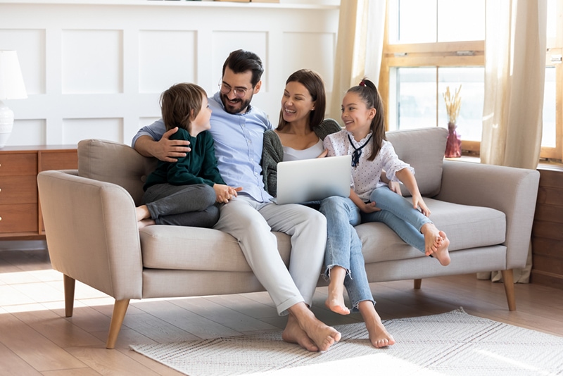 Eltern verbringen Zeit mit Kindern und sitzen auf der Couch im Wohnzimmer