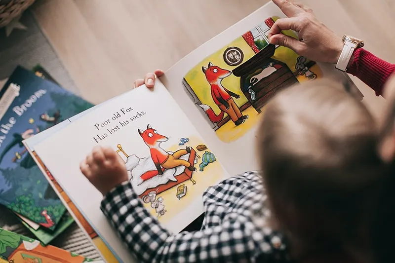 Frau liest einem kleinen Jungen ein Bilderbuch vor