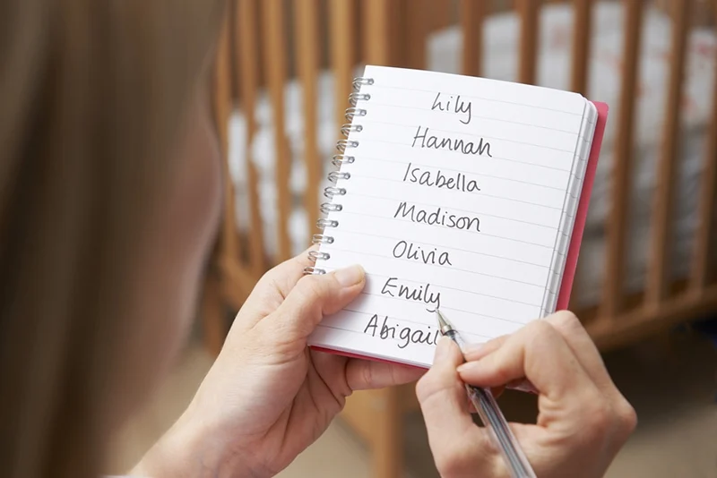 Frau schreibt mögliche Namen für kleines Mädchen im Kinderzimmer