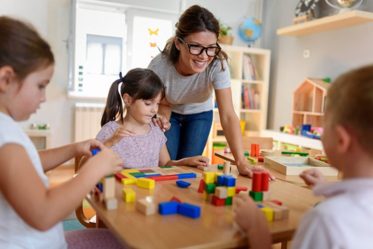 Kinder in der Kita spielen mit Lehrerin