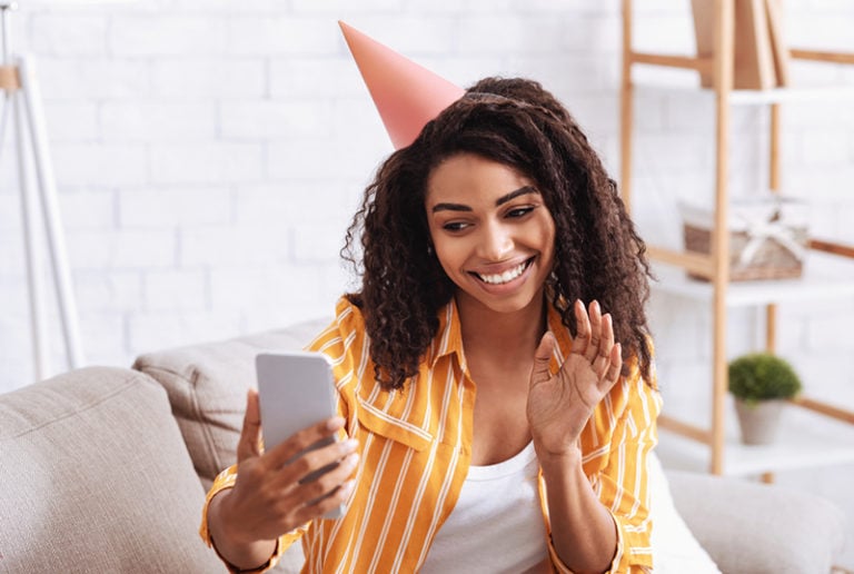 lächelnde Frau, die Geburtstag mit Videoanruf feiert