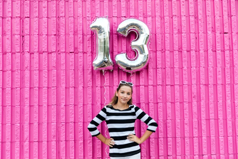 Mädchen, das den 13. Geburtstag feiert, steht in der Nähe von Ballons
