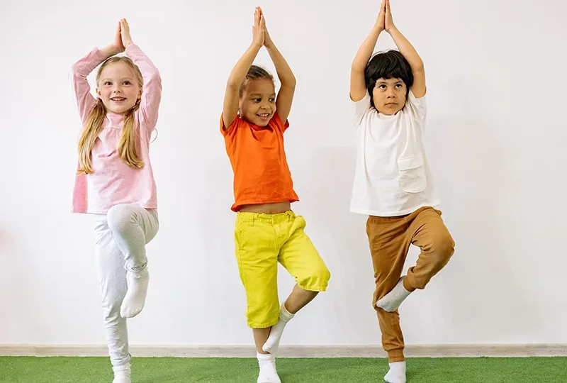 Gruppe von Kindern, die Yoga im Zimmer machen