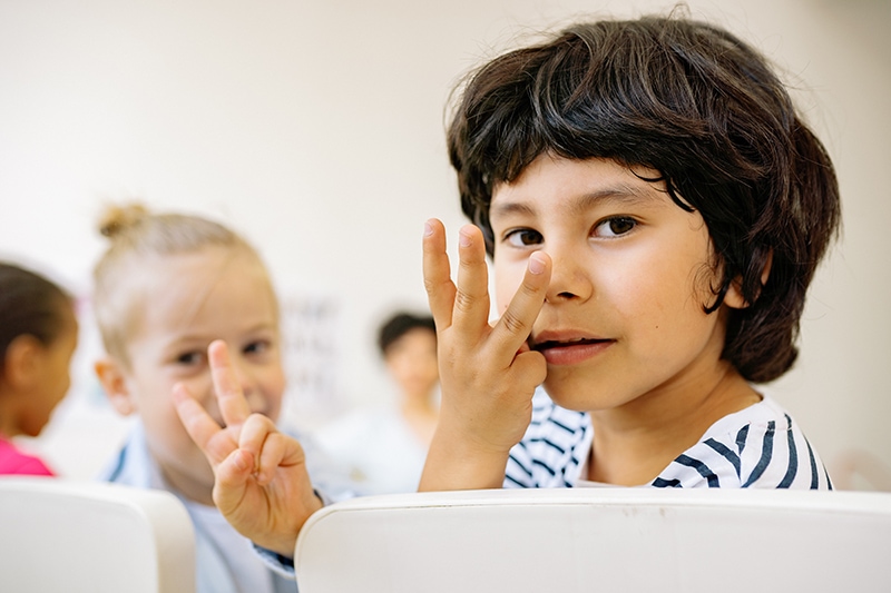 Junge und Mädchen zählen mit den Fingern, während sie auf Stühlen im Klassenzimmer sitzen
