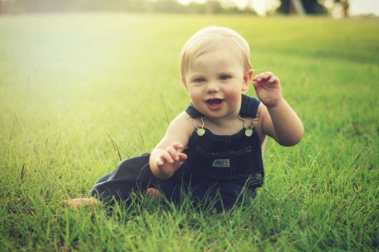 kleiner Junge sitzt auf dem Gras im Park