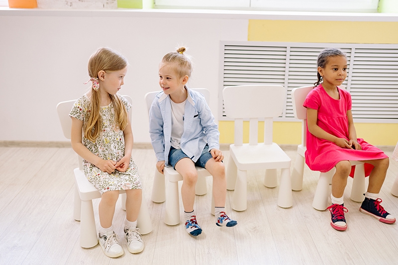 Kinder unterhalten sich im Kindergarten, während sie auf den Stühlen sitzen