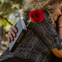 eine Person, die eine Bibel hält und eine weinende Frau umarmt