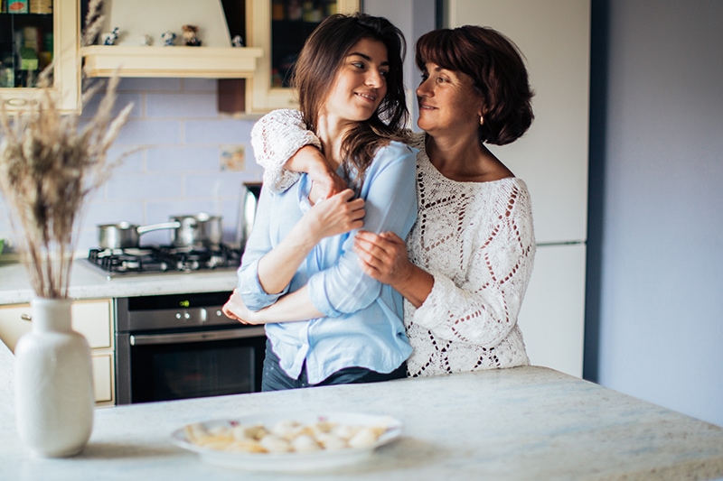 Mutter und Tochter umarmen sich in der Küche