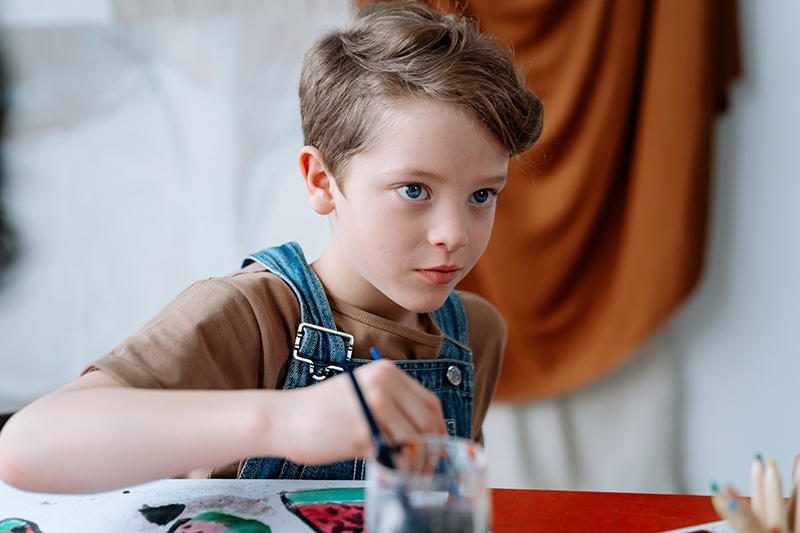 kleiner Junge malt auf Papier