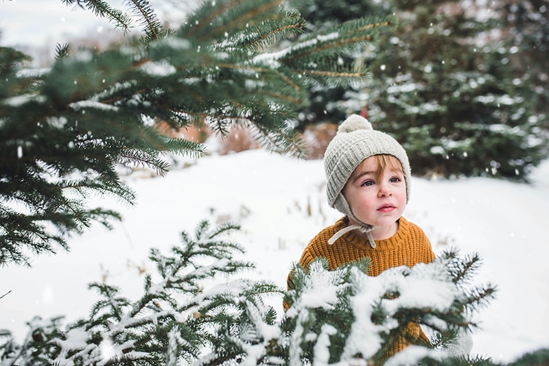 kleiner Junge mit Wollmütze, der auf dem Schnee steht