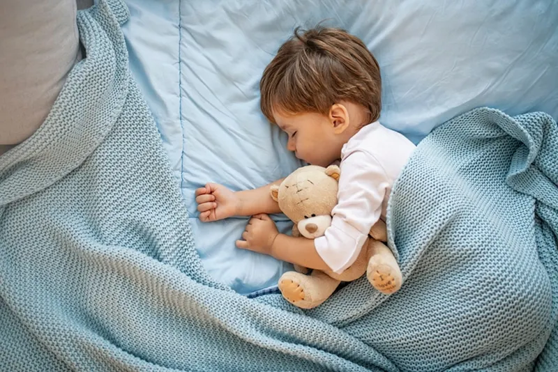 kleiner Junge schläft zusammen mit Teddybär