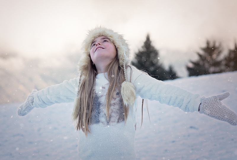 kleines Mädchen in weißer Jacke auf dem Schnee