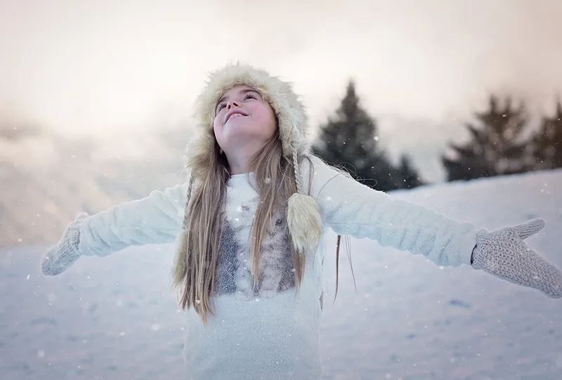 kleines Mädchen in weißer Jacke auf dem Schnee