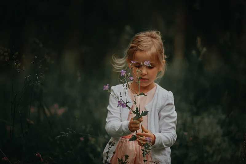 kleines Mädchen mit Blumen auf dem Feld