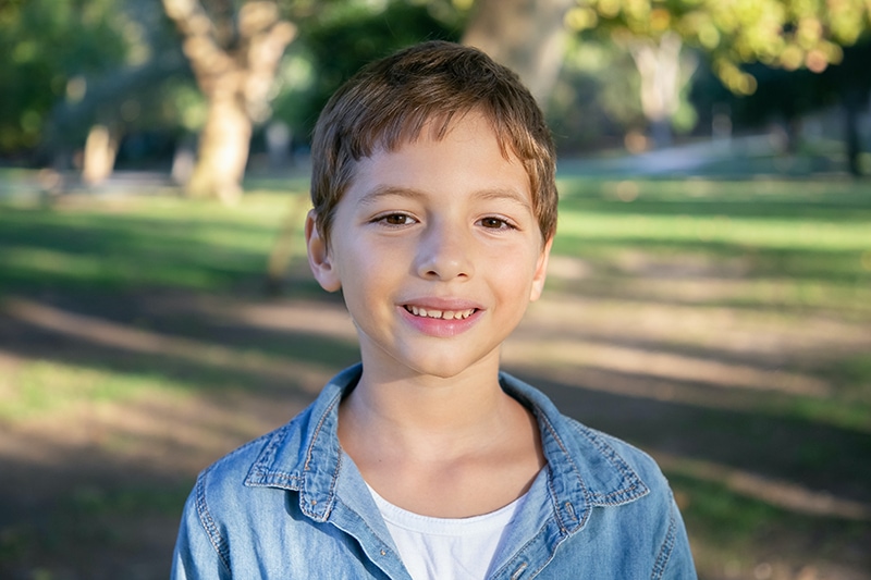 lächelnder kleiner Junge, der im Park steht