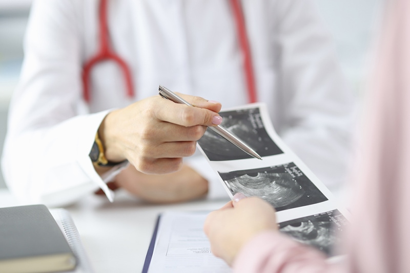 Arzt zeigt der schwangeren Frau in der Klinik die Ergebnisse des Ultraschalls