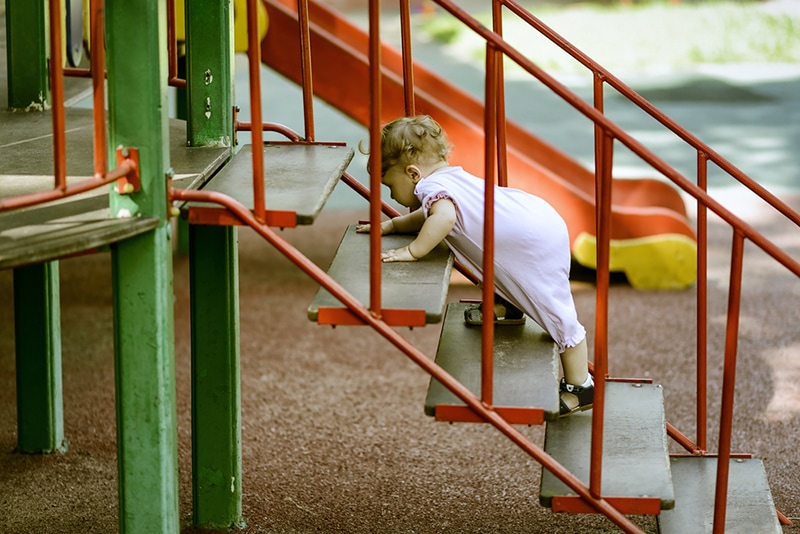 Baby klettert auf der Treppe auf dem Spielplatz