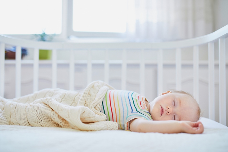 Babymädchen, das tagsüber im Beistellbett schläft