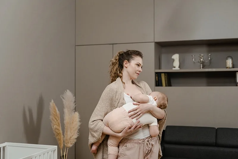 Frau trägt ihr Baby und stillt es