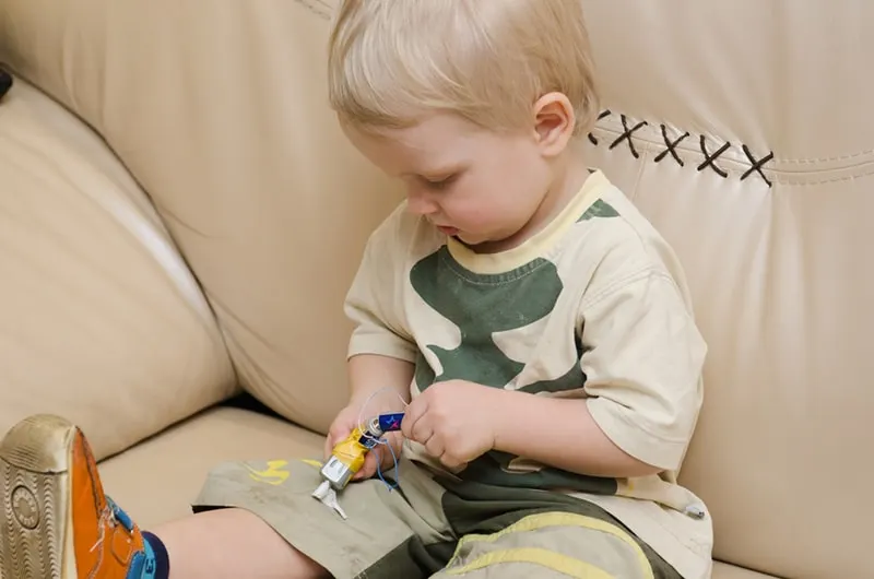Kind spielt mit Batterie und Motor auf dem Sofa zu Hause