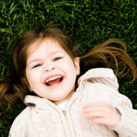 lächelndes kleines Mädchen, das auf dem Gras liegt