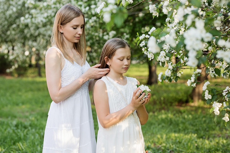 Mutter und Tochter stehen in der Nähe des Blumenbaums im Park