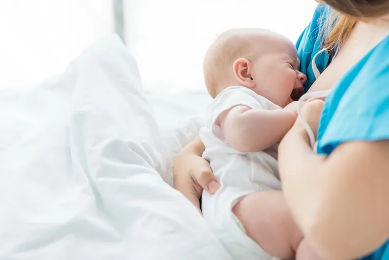 Neugeborenes Baby weint, während Mutter versucht, es zu stillen