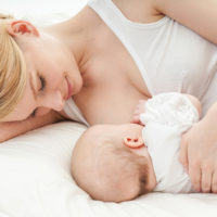 Mutter stillt ihr Baby auf dem Bett